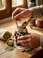 Load image into Gallery viewer, Hands filling the cowhide torpedo mate gourd with loose yerba mate
